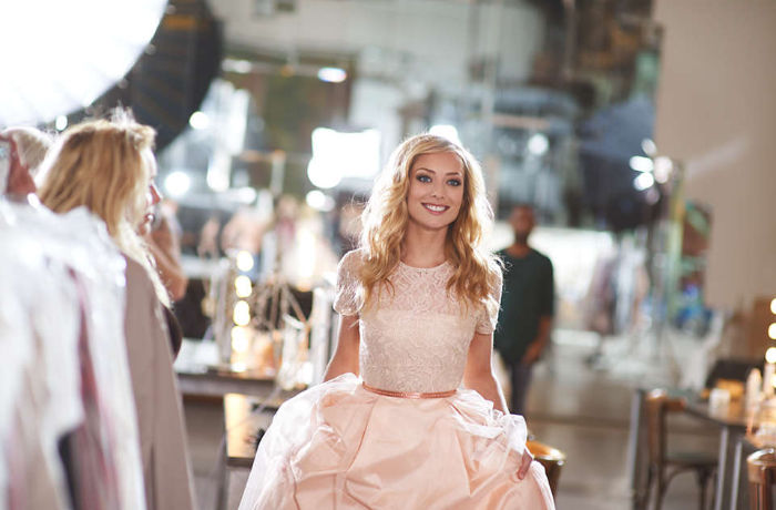 Egy halv&aacute;ny r&oacute;zsasz&iacute;n ruh&aacute;s nő arc&aacute;n sz&eacute;les mosollyal felfedi gy&ouml;ngyh&aacute;zfeh&eacute;r fogsor&aacute;t.