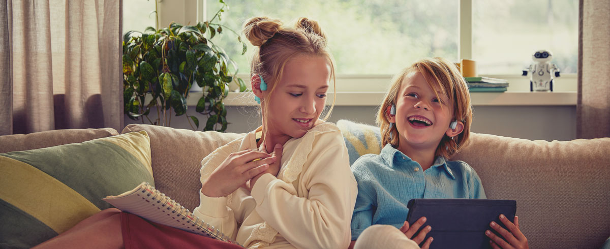Philips open-ear kialak&iacute;t&aacute;s&uacute; gyermek fejhallgat&oacute;t haszn&aacute;l&oacute;, vide&oacute;t n&eacute;ző gyerekek